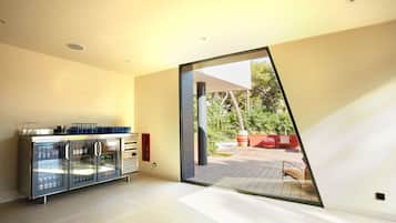 Un interior moderno con cocina de frentes de vidrio, puerta corrediza que da a un patio exterior y un diseño minimalista.