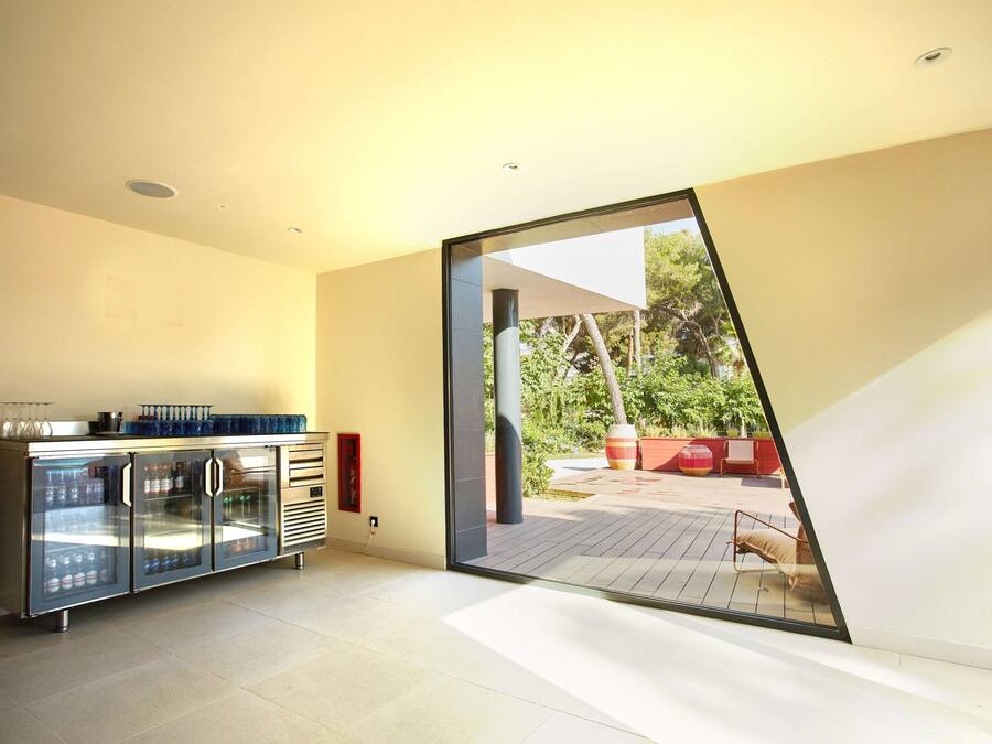 Un interior moderno con cocina de frentes de vidrio, puerta corrediza que da a un patio exterior y un diseño minimalista.
