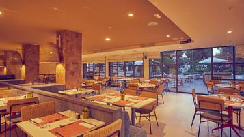 Un restaurante espacioso con techos altos, amplios ventanales y diferentes opciones de asientos, como mesas y sillas.