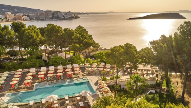 Un resort con zona de piscina, asientos al aire libre y vista al mar.
