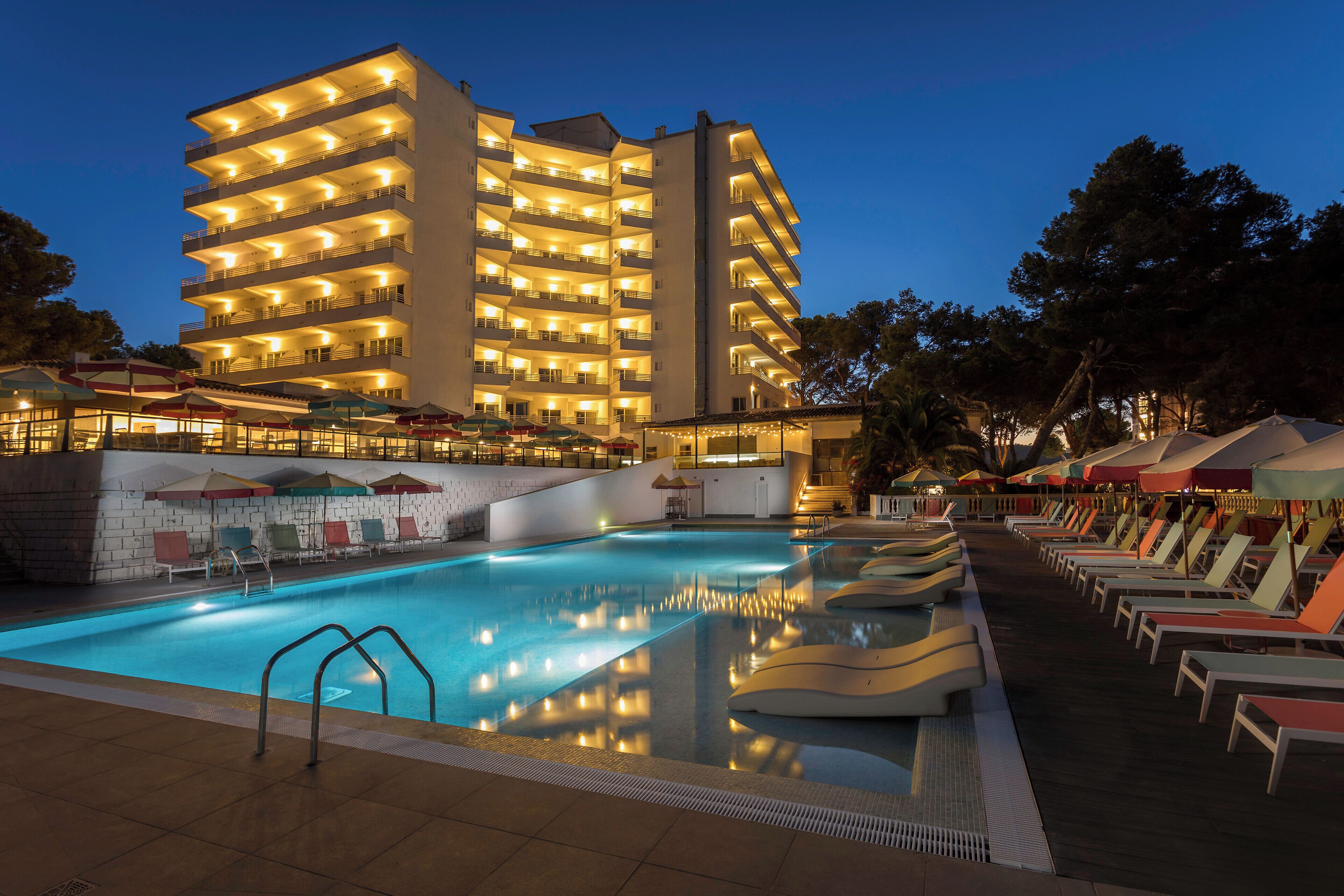 Un hotel con piscina, diversi balconi e aree salotto all'aperto.