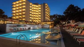 A hotel with a swimming pool, multiple balconies, and outdoor seating areas.