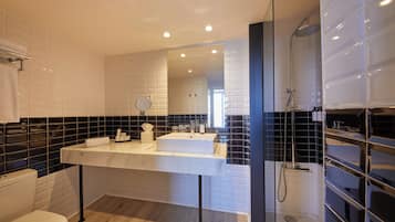Een moderne badkamer met een wit wastafelmeubel, zwart betegelde wanden en een douchecabine met glazen wanden.