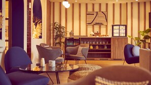 Una sala de estar moderna con una mesa redonda, dos sillones, una estantería y un panel decorativo en la pared.