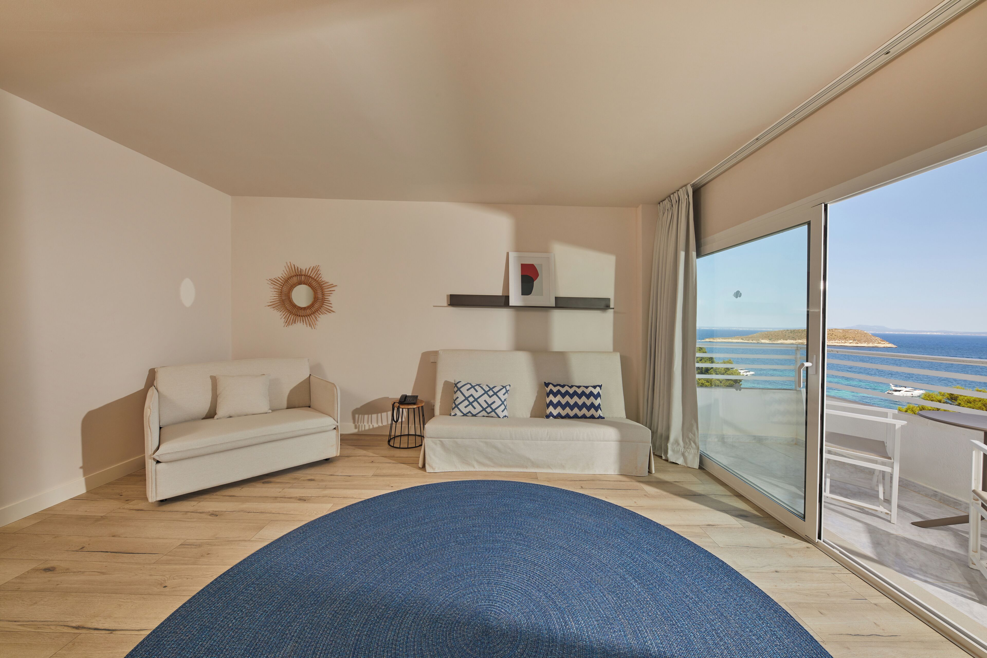 Una habitación moderna con un ventanal grande, un sofá, una mesita y una alfombra azul.
