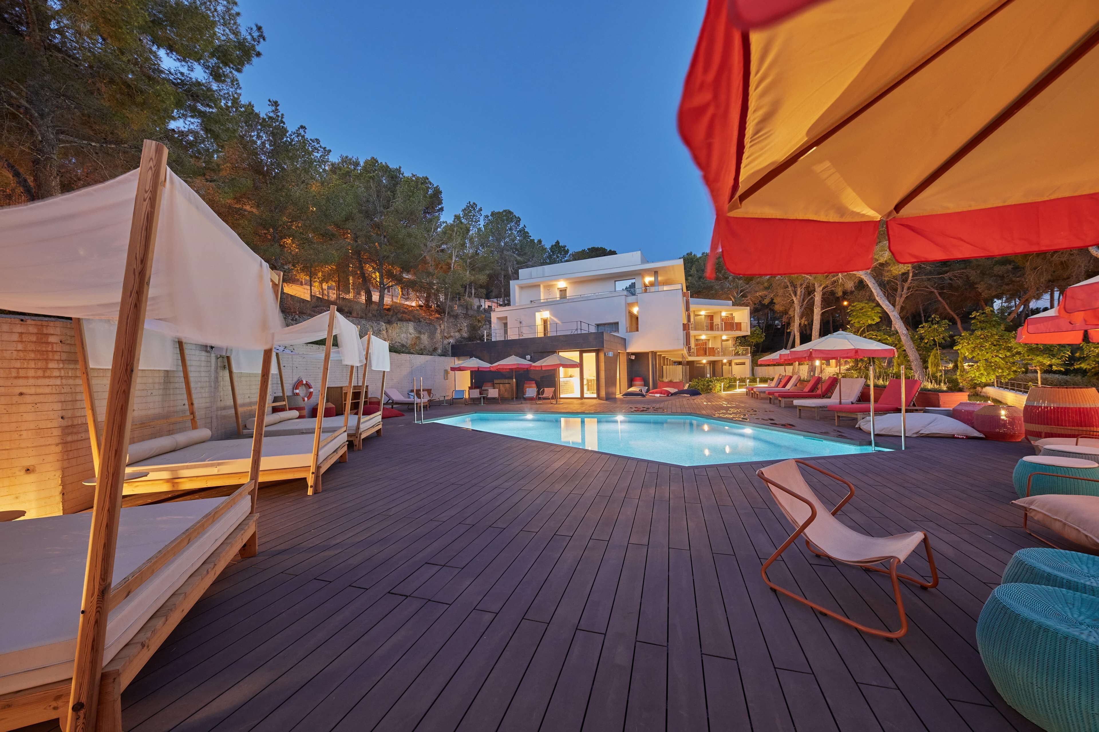 A poolside area with wooden deck, lounge chairs, and umbrellas.
