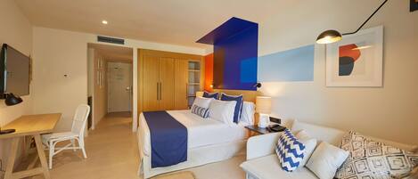 A hotel room with a bed, a desk, a chair, a sofa, and a small table.