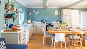Una cocina moderna con armarios blancos, una mesa de comedor de madera y una pared azul.