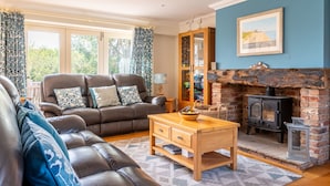 Ein Wohnzimmer mit Ledersofa, Couchtisch aus Holz, Kamin aus Ziegelsteinen und Bücherregal.
