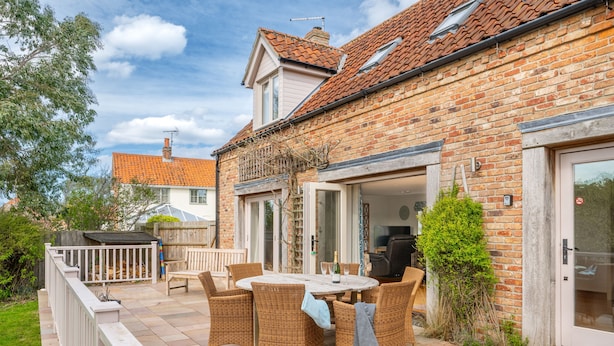 Eine Terrasse mit Korbmöbeln, einem Tisch und einem Grill.