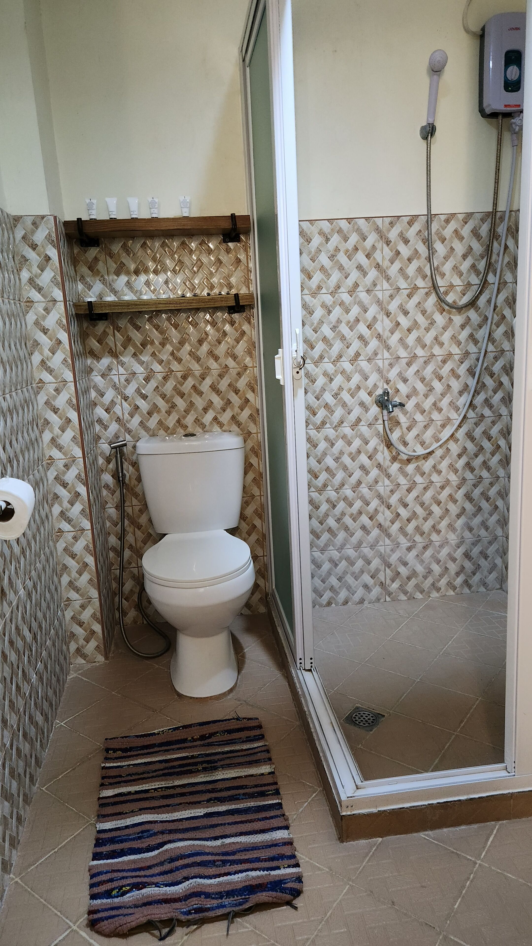 A bathroom with a toilet, a shower, and a patterned wall.