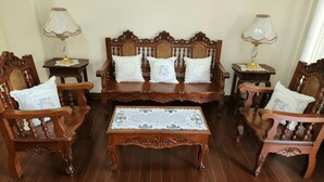 A traditional wooden furniture set with a central sofa, two armchairs, and a coffee table, all with intricate carvings. - Balay ni Manuel ken Maria Boutique Hotel (San Fernando)