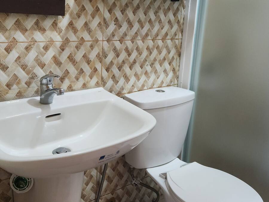 Un bagno con un lavandino bianco, due servizi igienici, uno specchio e una mensola in legno sopra il lavandino.