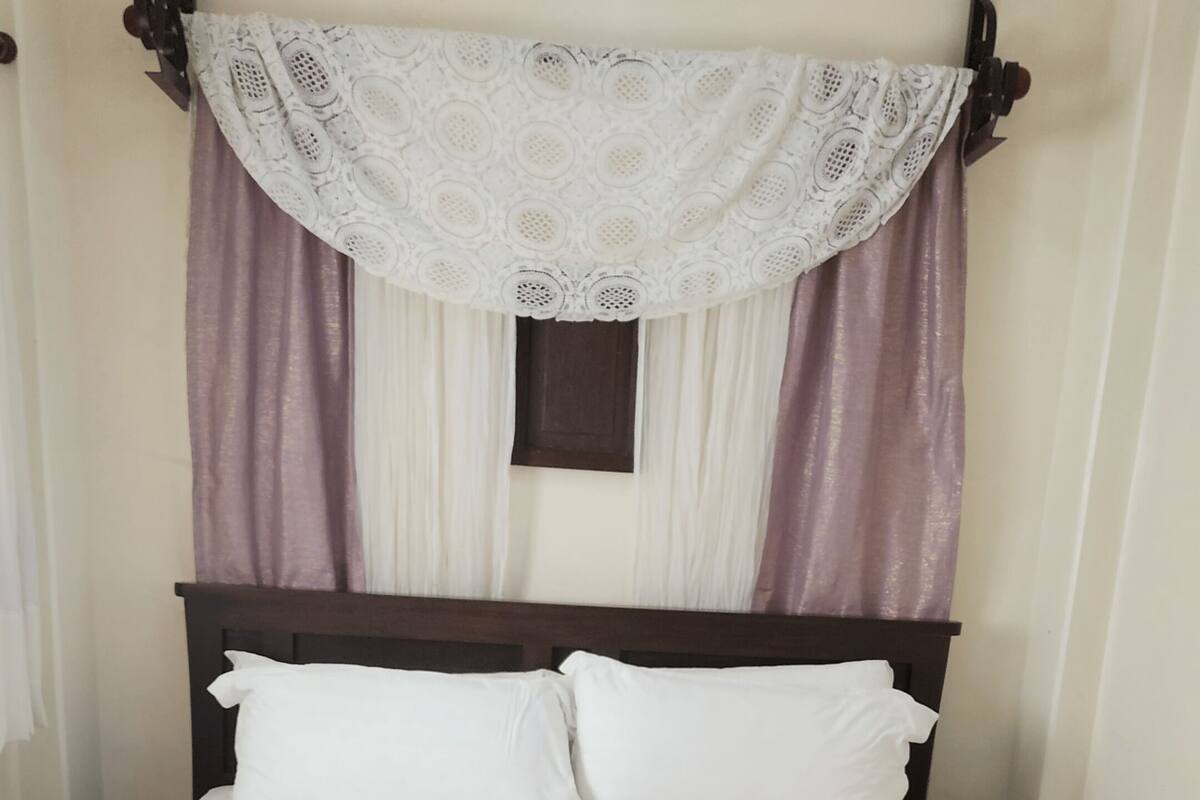 Ein Bett mit Holzrahmen, weißer Bettwäsche und einer violetten Decke.