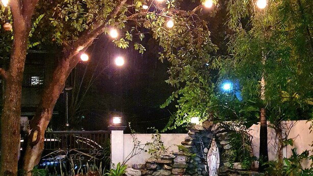 An outdoor garden area with a stone pathway, a small pond, and a seating area under trees. - Balay ni Manuel ken Maria Boutique Hotel (San Fernando)