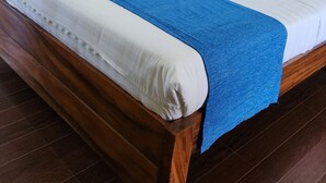 A neatly made bed with white and blue bedding, a wooden headboard, and a nightstand with a lamp. - Balay ni Manuel ken Maria Boutique Hotel (San Fernando)
