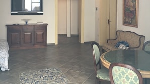 A spacious living area with a high ceiling, a dining table with chairs, a sofa, a television, and a staircase leading to an upper level. - La Querencia (Palermo)