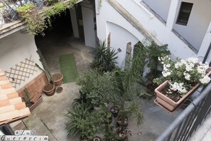A courtyard with potted plants and a green mat. - La Querencia (Palermo)