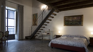 A bedroom with a bed, a staircase, a window, a chair, and a painting on the wall. - La Querencia (Palermo)