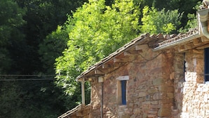 A stone building with a rustic appearance, featuring a small courtyard with a table and a stone fountain.