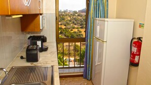 Eine kleine Küche mit Fenster, einem Toaster, einem Kühlschrank und einem Feuerlöscher.