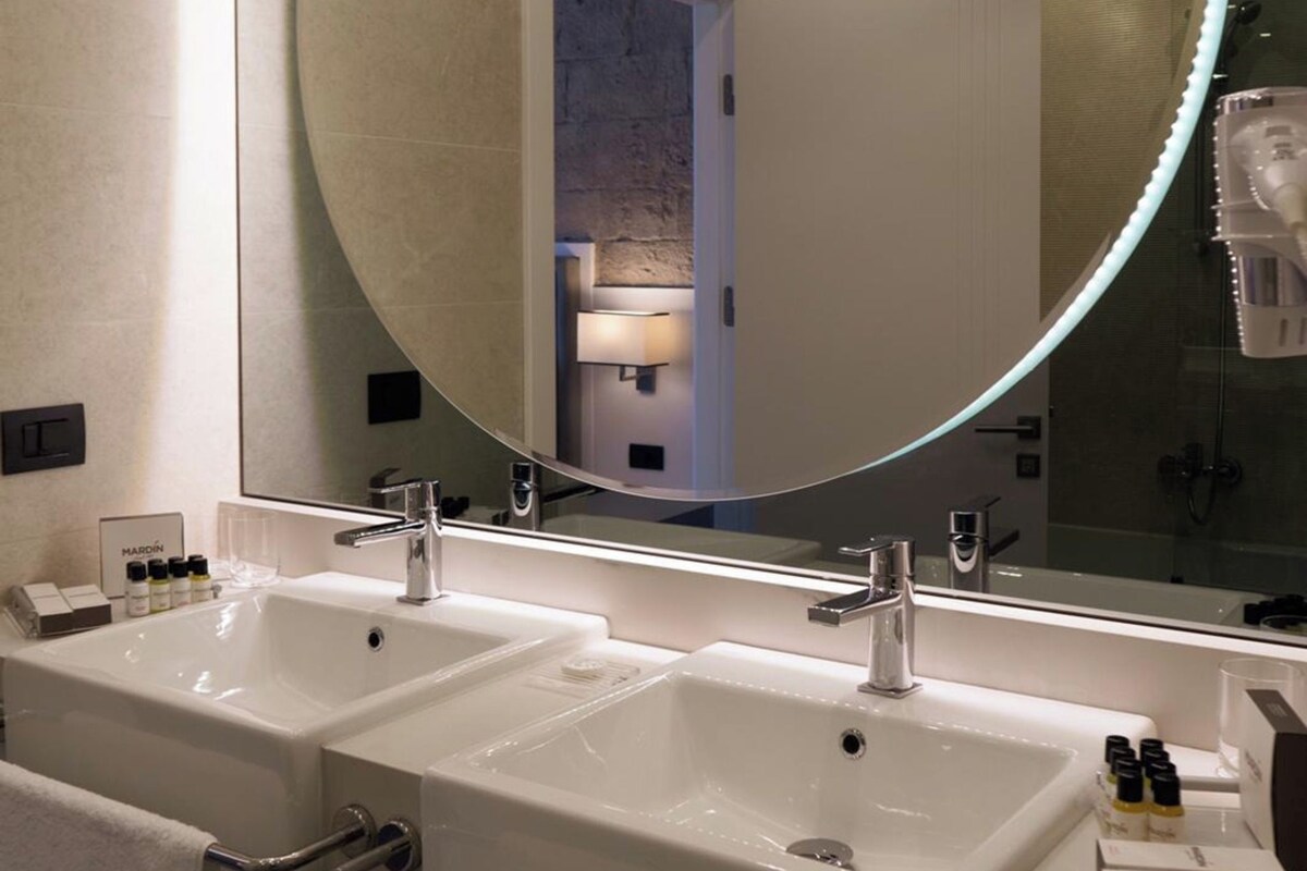 Un baño moderno con dos lavamanos, un espejo grande y un perchero para toallas.