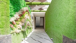 A corridor with green artificial grass walls and a tiled floor. - Hotel Oyster Suite (Mumbai)