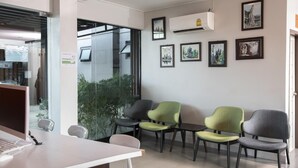 A modern office with a reception desk, four chairs, and framed artwork on the wall. - At Border (Aranyaprathet)