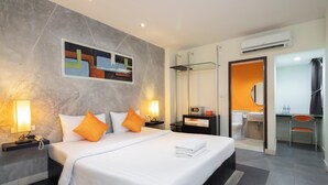 A modern hotel room with a large bed, two bedside tables with lamps, a glass shower enclosure, a bathroom with a sink and mirror, and a small seating area. - At Border (Aranyaprathet)
