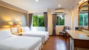 Ein Hotelzimmer mit zwei Betten, einem Schreibtisch, einem Stuhl und einem großen Fenster mit Vorhängen.