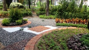 Ein angelegter Garten mit Kiesweg, Ziegelbordur und verschiedenen Pflanzen.