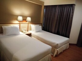 Habitación de hotel con dos camas, una mesita de noche con teléfono y una lámpara.