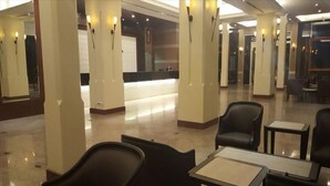Eine Hotelhalle mit einer Rezeption, mehreren Sitzbereichen und einem polierten Boden.