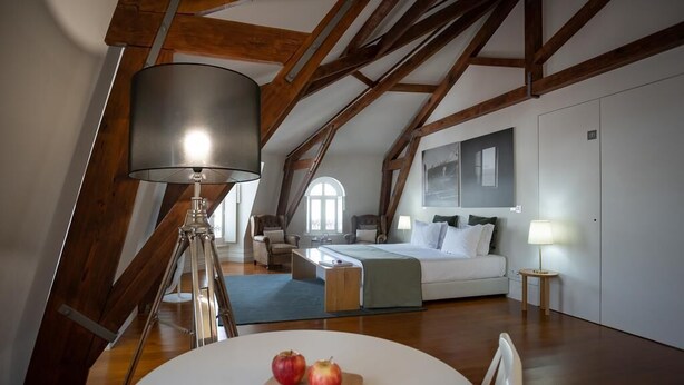 Camera da letto in stile loft moderna con travi a vista in legno, un'ampia finestra, un letto, una scrivania e un tavolo da pranzo con delle mele.
