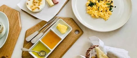 A breakfast setting with scrambled eggs, ham, and a croissant on a white table.