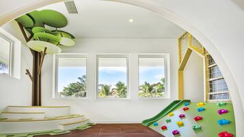 Kids can climb, slide, and play amidst a lush view of palm trees.