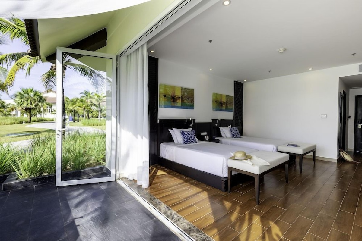 A modern hotel room with a large bed, a small table, and a view of palm trees.