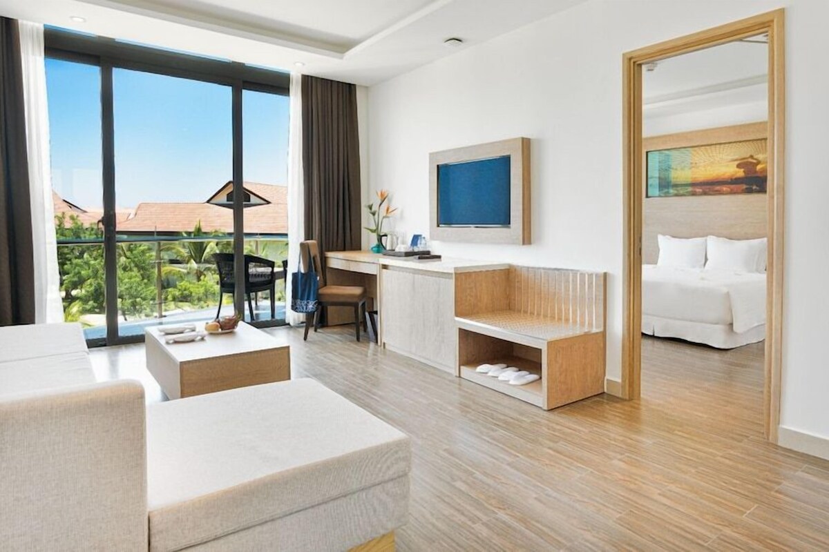Ein Hotelzimmer mit Balkon, Schreibtisch, Bett und Fernseher.