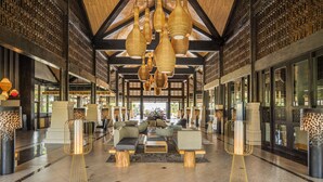 Un hall d’entrée spacieux avec de hauts plafonds, des lampes suspendues en osier et un mobilier moderne.