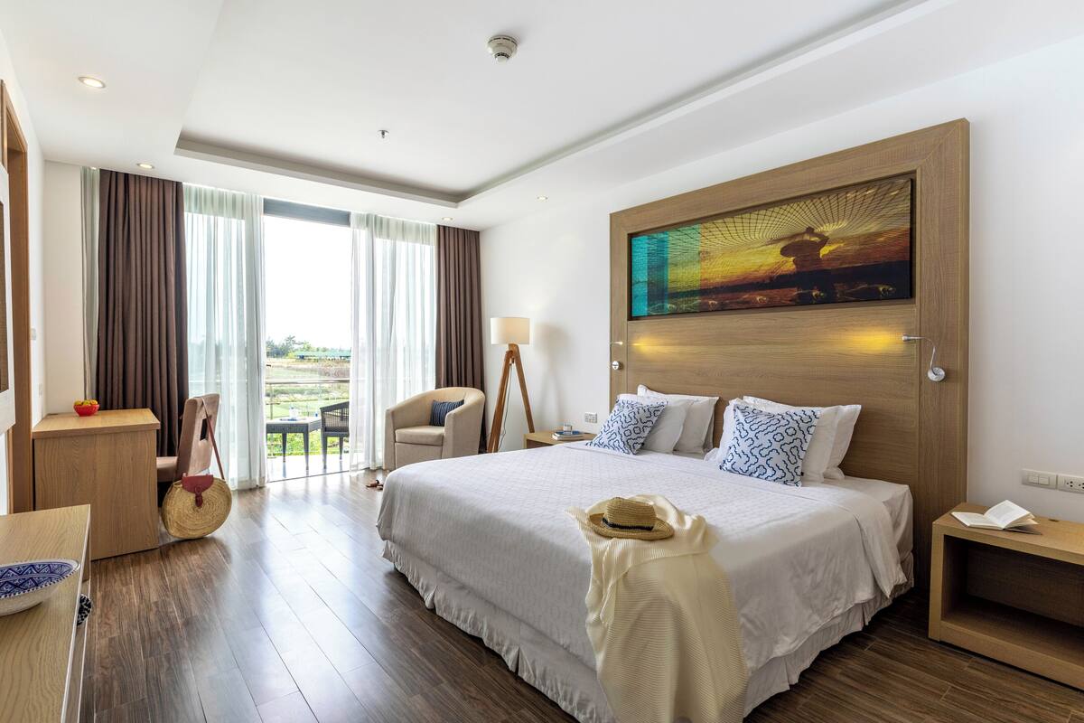 Habitación de hotel con una cama grande, un escritorio, una silla, una mesa de comedor y vistas al exterior.