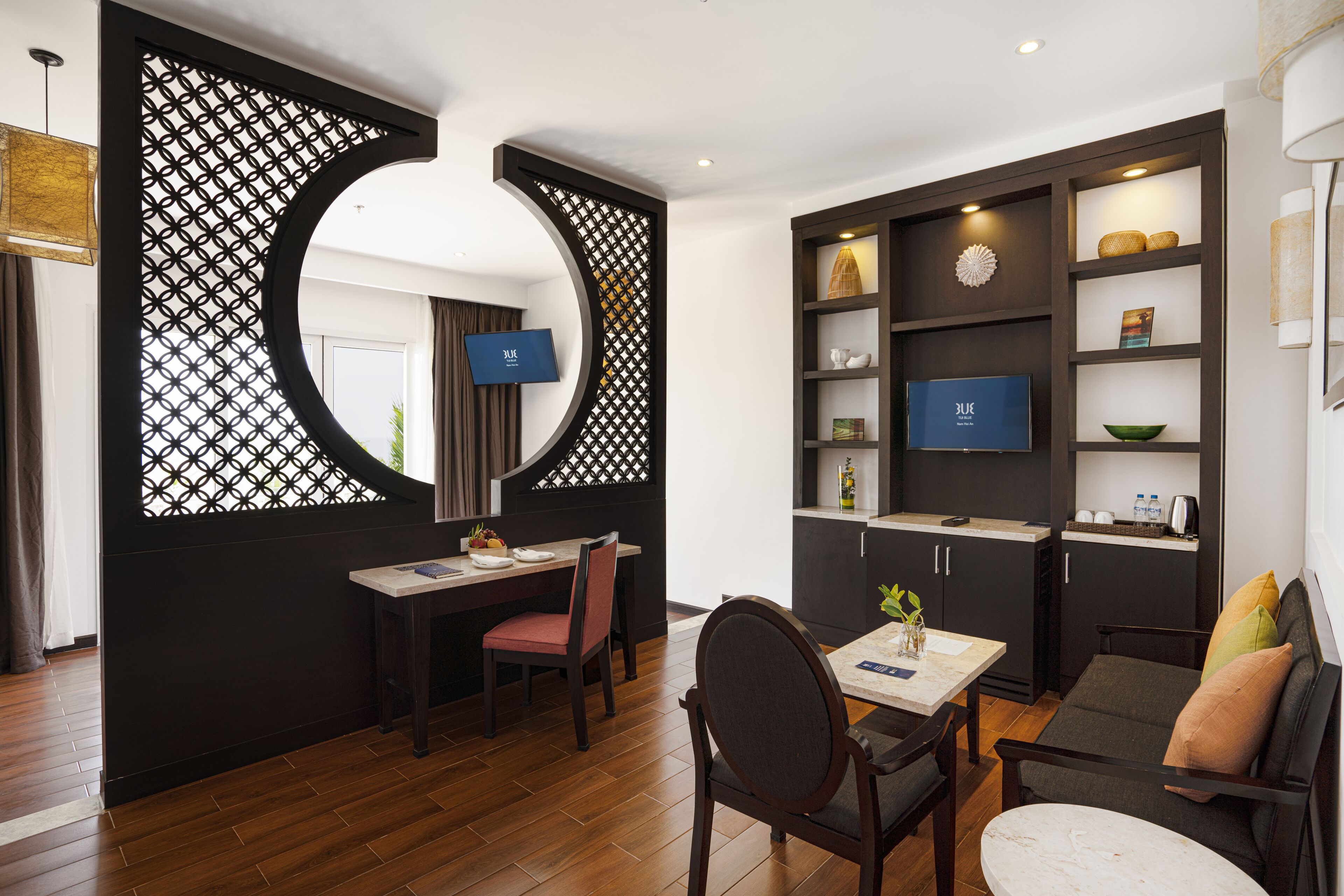 A modern living room with a dining area, a kitchen, and a TV mounted on the wall.