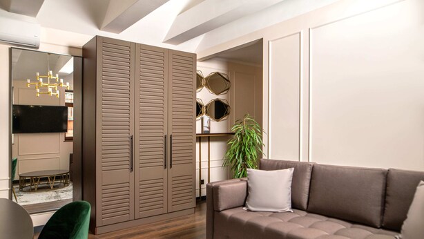 A modern living room with a brown sofa, green chair, and a large wardrobe. - De Paris Apartments (Kyiv)