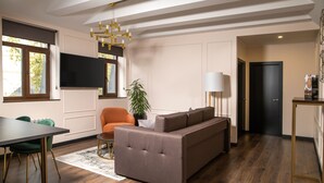 A modern living room with a sofa, a dining table, and a TV mounted on the wall. - De Paris Apartments (Kyiv)