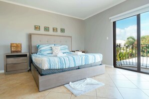 A bedroom with a bed, a nightstand, a small table, a window with a view, and a balcony. - Beautiful House with Private Pool in Noord (Noord)