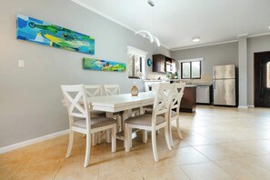 A modern kitchen with white cabinetry, a stainless steel refrigerator, and a dining area with a white table and chairs. - Beautiful House with Private Pool in Noord (Noord)
