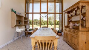 Zona pranzo con tavolo di legno, sedie, un'alta credenza in legno con stoviglie e una libreria.