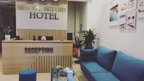 Een receptiebalie van hout met de tekst 'New Skyairport Hotel' en klokken die de tijd in Parijs, Hanoi en New York weergeven.