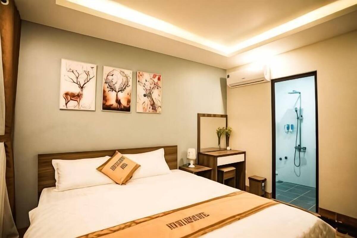 Une chambre d’hôtel comprenant un lit, une table de chevet, un miroir et un espace douche.