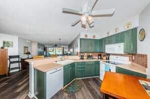 A kitchen with green cabinets, a white microwave, and a ceiling fan.
