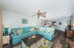 A living room with a sectional sofa, a coffee table, and a ceiling fan.